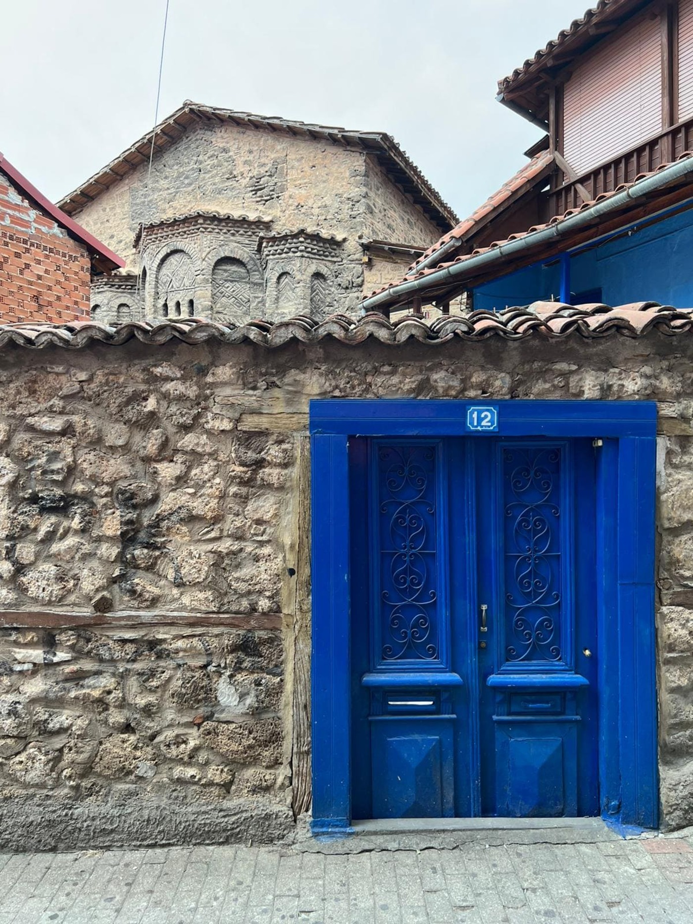 strahlendblaue, zweiflügelige Tür, geschlossen, Bruchstein, im Hintergrund die Kirche St. Cyricus und Julitta, Veria