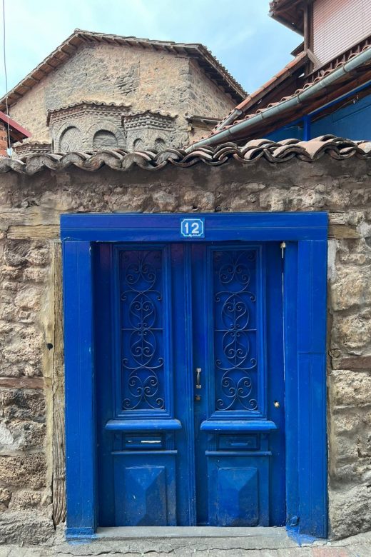 Strahlendblaue Tür, mit zwei Flügeln, geschlossen, Bruchstein, im Hintergrund die Kirche St. Cyricus und Julitta
