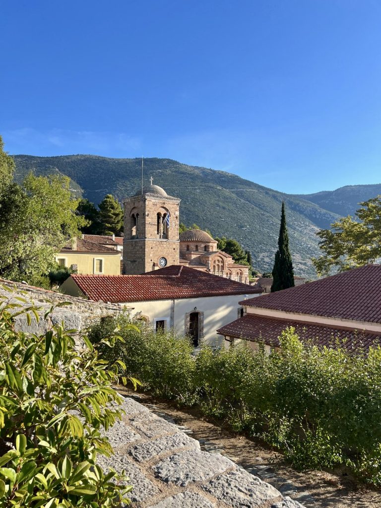 Blick auf Kirche, Dorf, Dächer, blauer Himmel, im Vordergrund eine Steinmauer